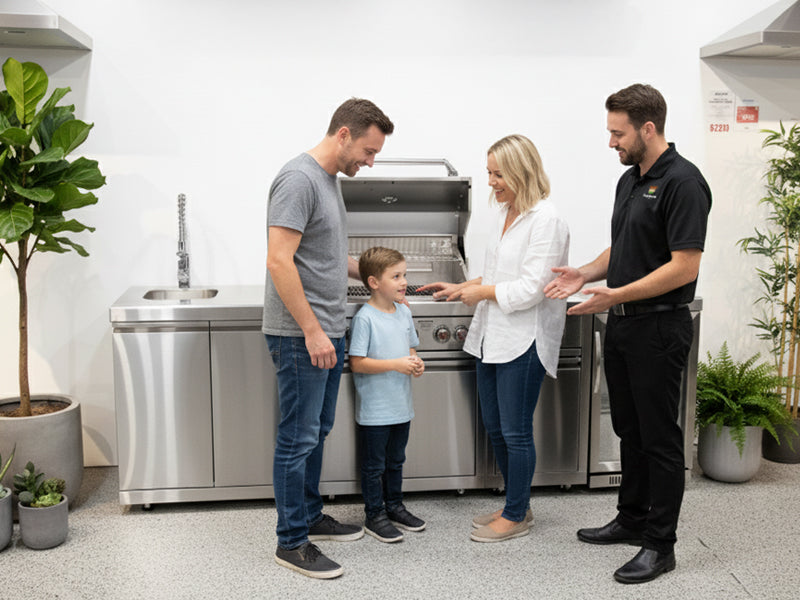 A entertaining-loving family, talking with a friendly outdoors domain team member looking at BBQ kitchens examining a modular BBQ outdoor kiutchen and grill in our Melbourne store in a showroom.
